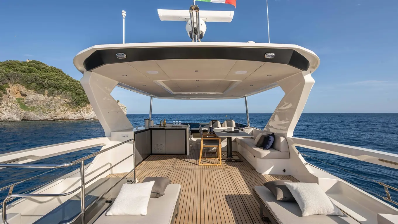 Luxurious yacht deck with sun loungers, ocean view, and a Portuguese flag. A stylish outdoor dining area is visible.
