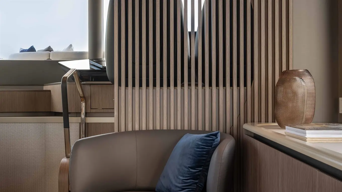 Modern interior featuring a brown swivel chair with a blue cushion, wooden slatted partition, and a stylish vase on the counter.
