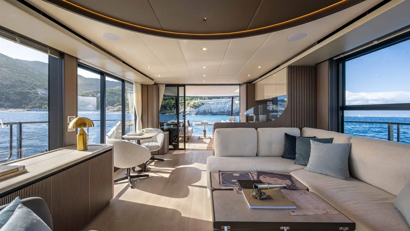 Luxurious yacht interior with modern furnishings, large windows, sweeping sea views, and stylish light fixtures.