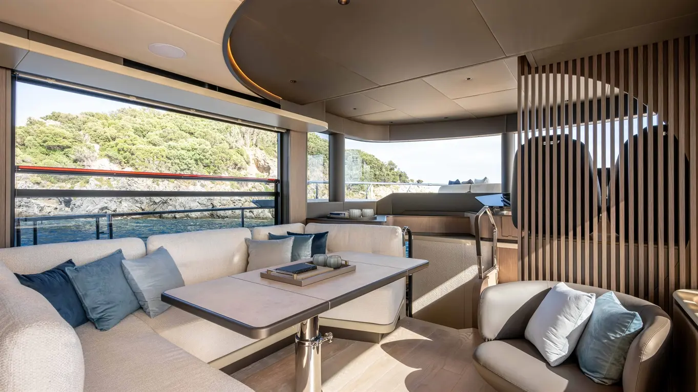 Modern yacht interior featuring a spacious lounge with plush seating, elegant table, and scenic coastal views.