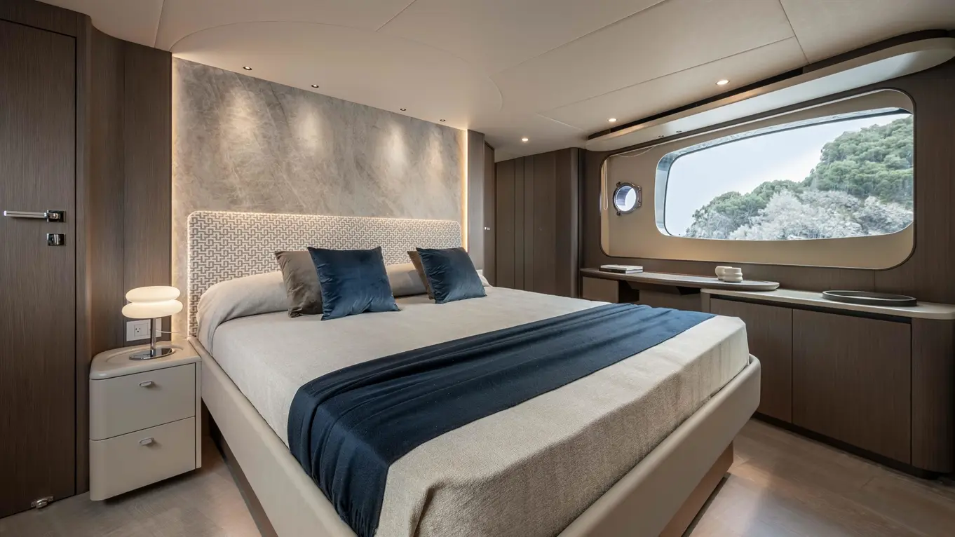Modern bedroom featuring a large bed with decorative cushions, ambient lighting, and a scenic window view of greenery.