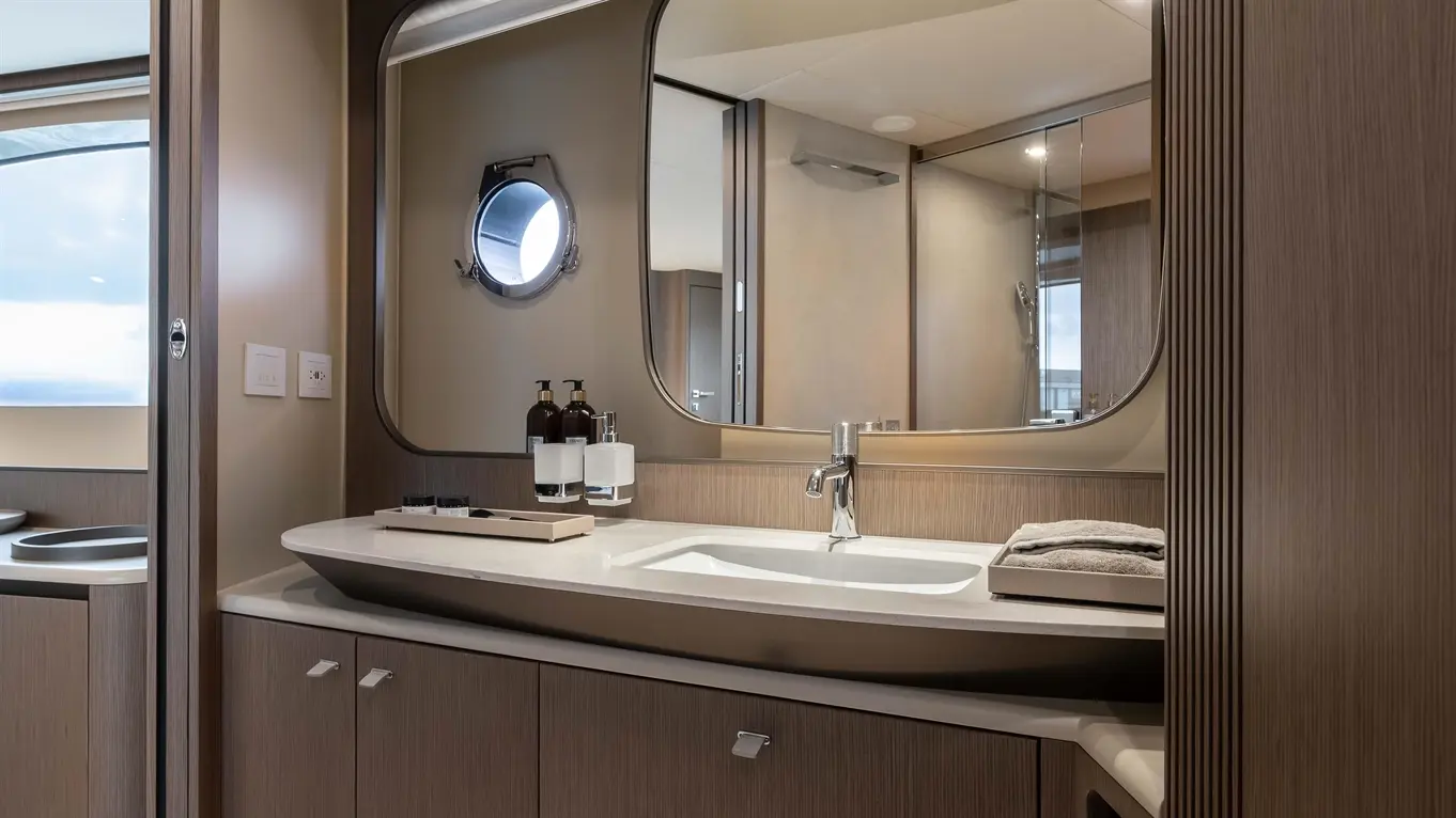 Luxury bathroom interior featuring a stylish sink, shelves with toiletries, and a large mirror, with soft ambient lighting.