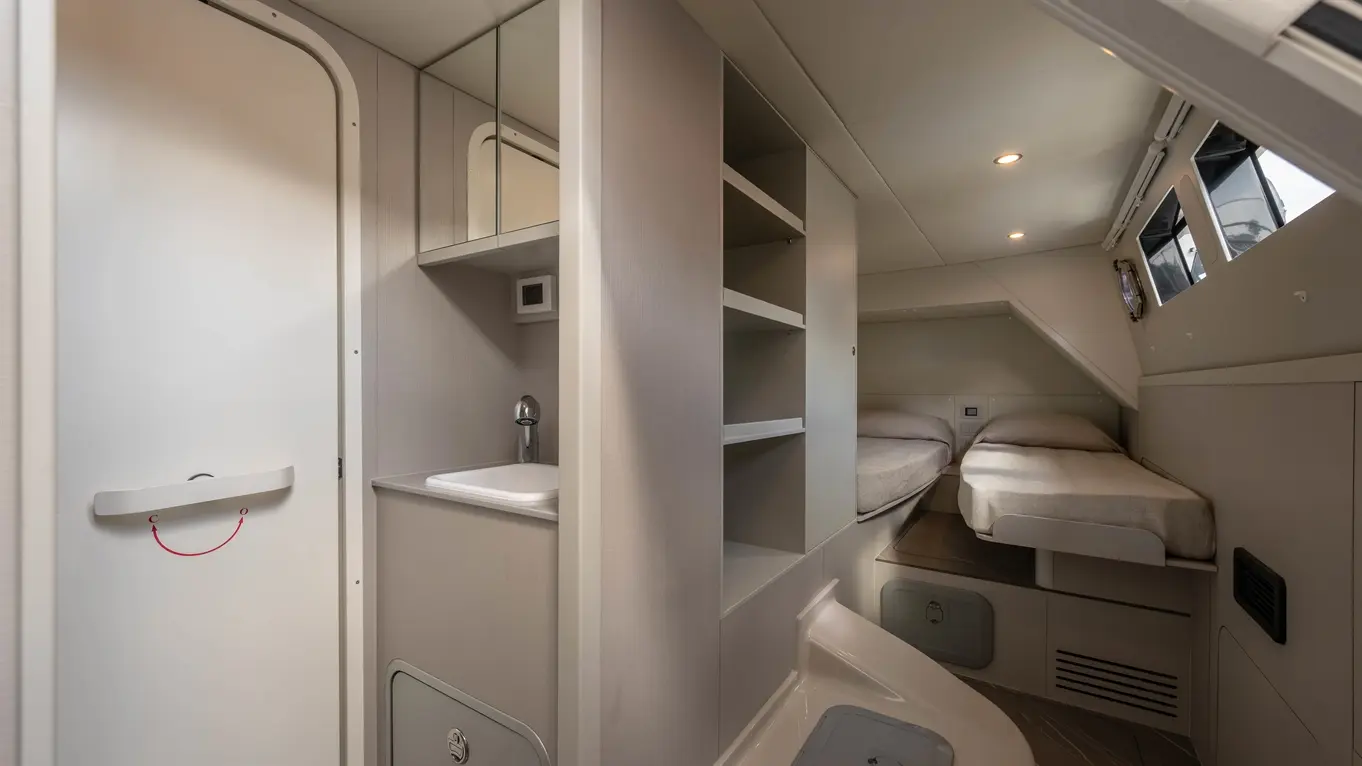 Interior view of a cabin featuring twin beds, a wash basin, storage shelves, and a bathroom door. Modern and spacious design.