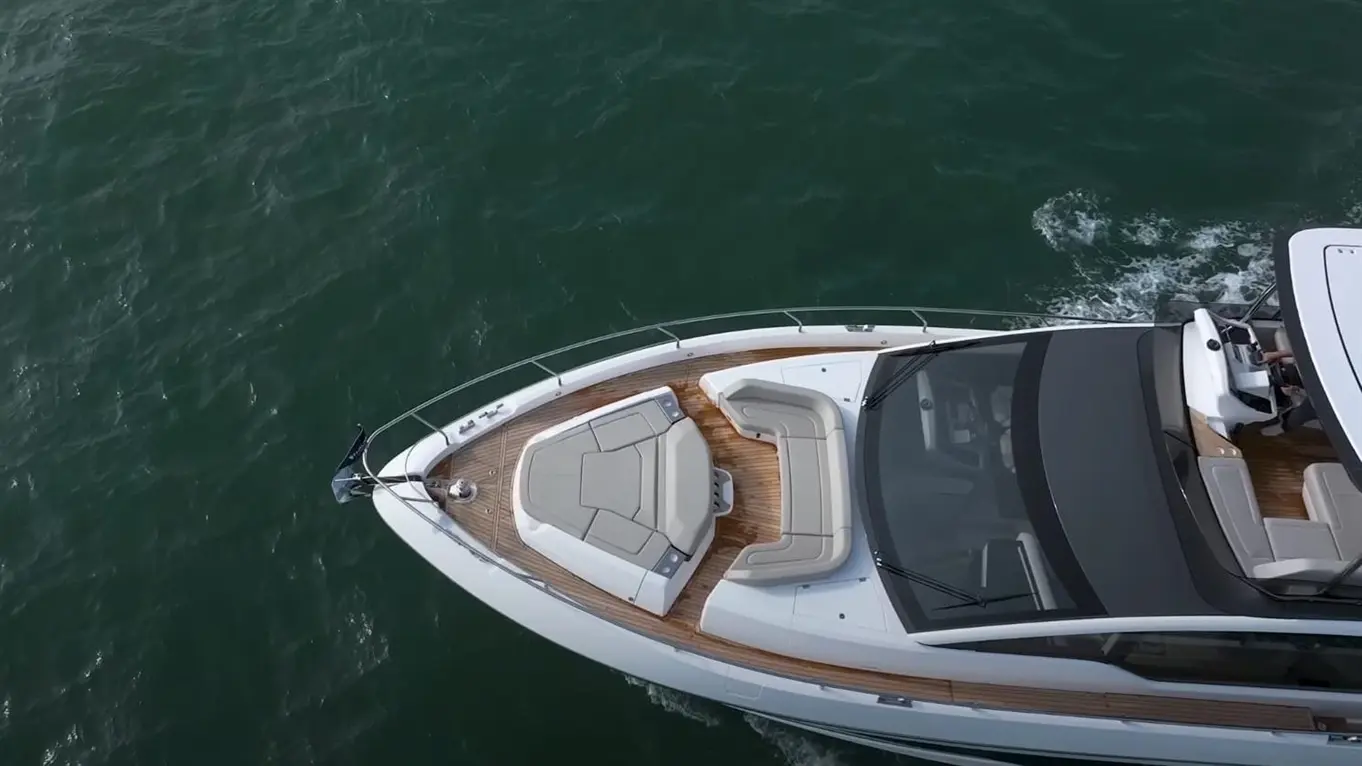 Aerial view of a luxury motorboat with a spacious seating area, gliding over calm water, showcasing sleek design and elegance.