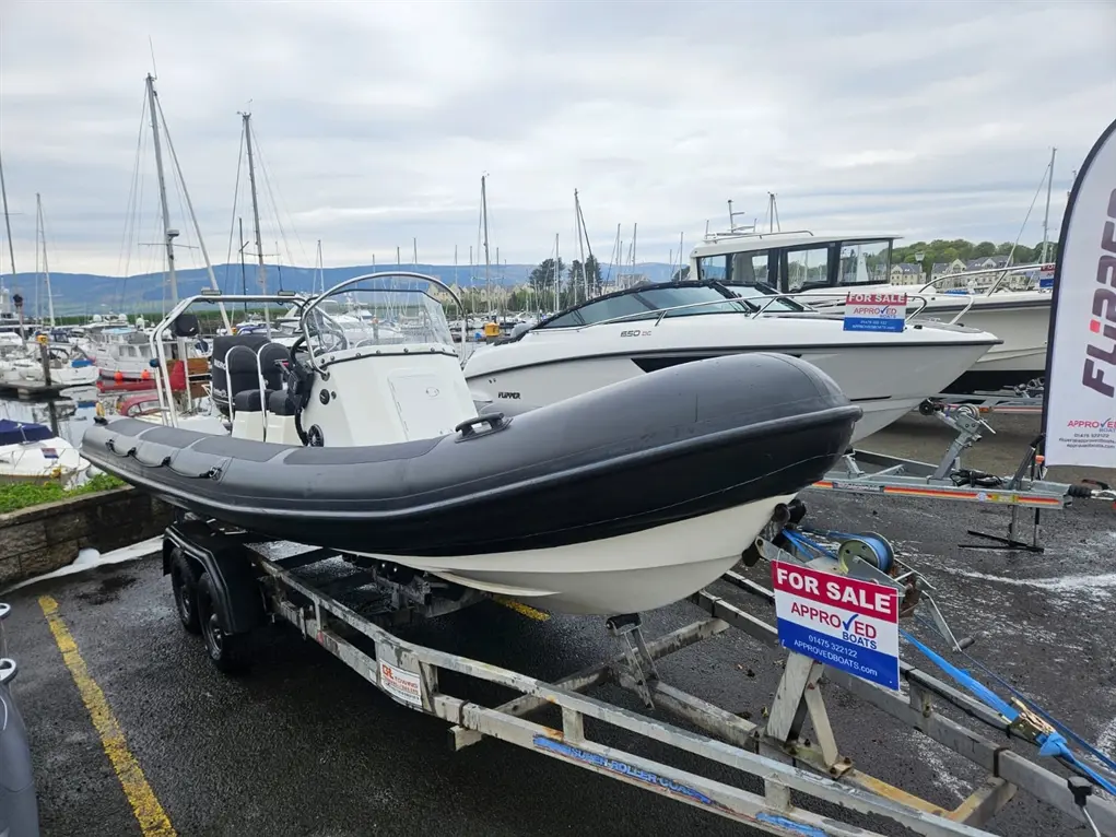 Rigid inflatable boat on a trailer at a marina, with a 