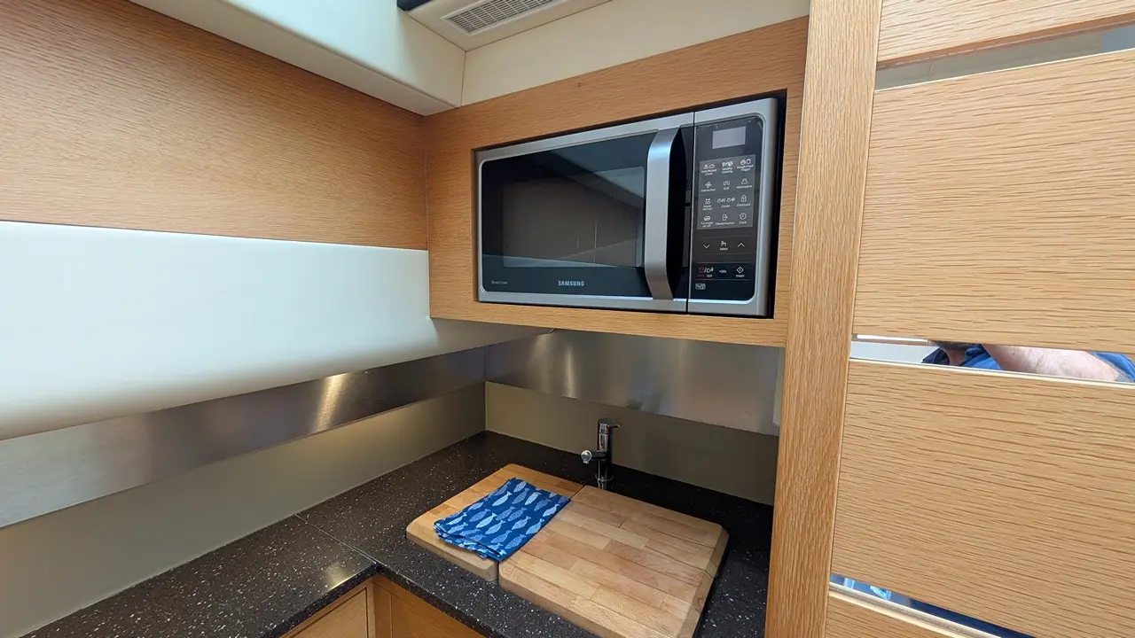 Modern kitchen featuring a Samsung microwave, wooden countertop, cutting board, and blue kitchen towel.