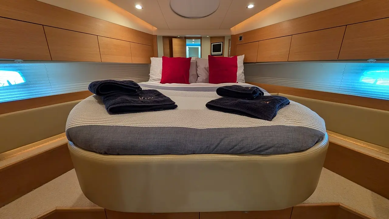 Luxury boat cabin featuring a double bed with red cushions, plush towels, and soft ambient lighting.