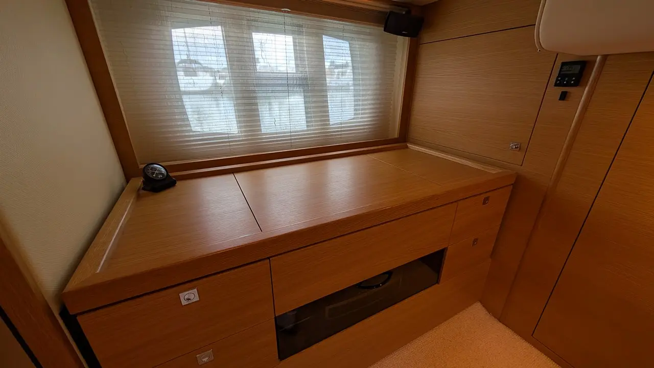 Modern wooden console table with drawers, a clock, and natural light from a window with blinds visible in the background.