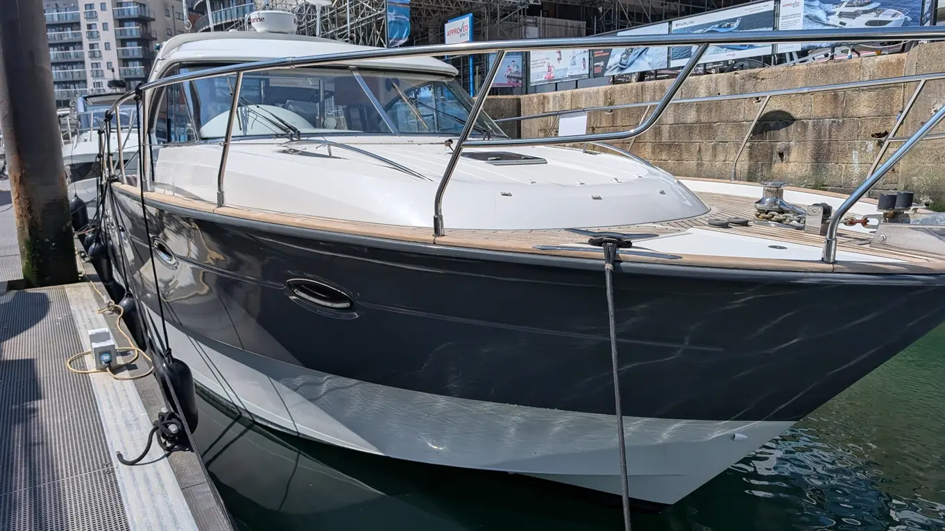 A luxury yacht docked at a marina, featuring a sleek black and white design, surrounded by water and buildings in the background.