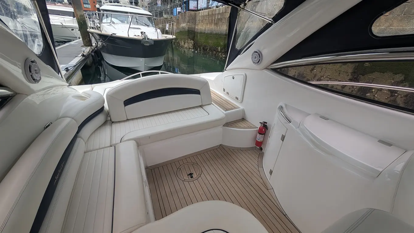 Interior view of a yacht featuring a spacious seating area, wooden flooring, and a fire extinguisher mounted nearby.