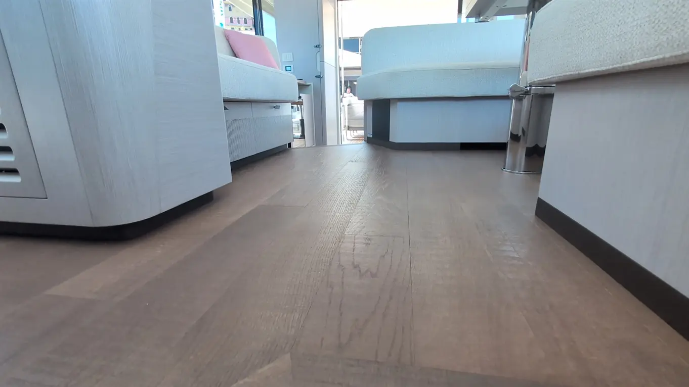 Interior view of a modern space with sleek furniture and wooden flooring, leading towards a bright doorway.