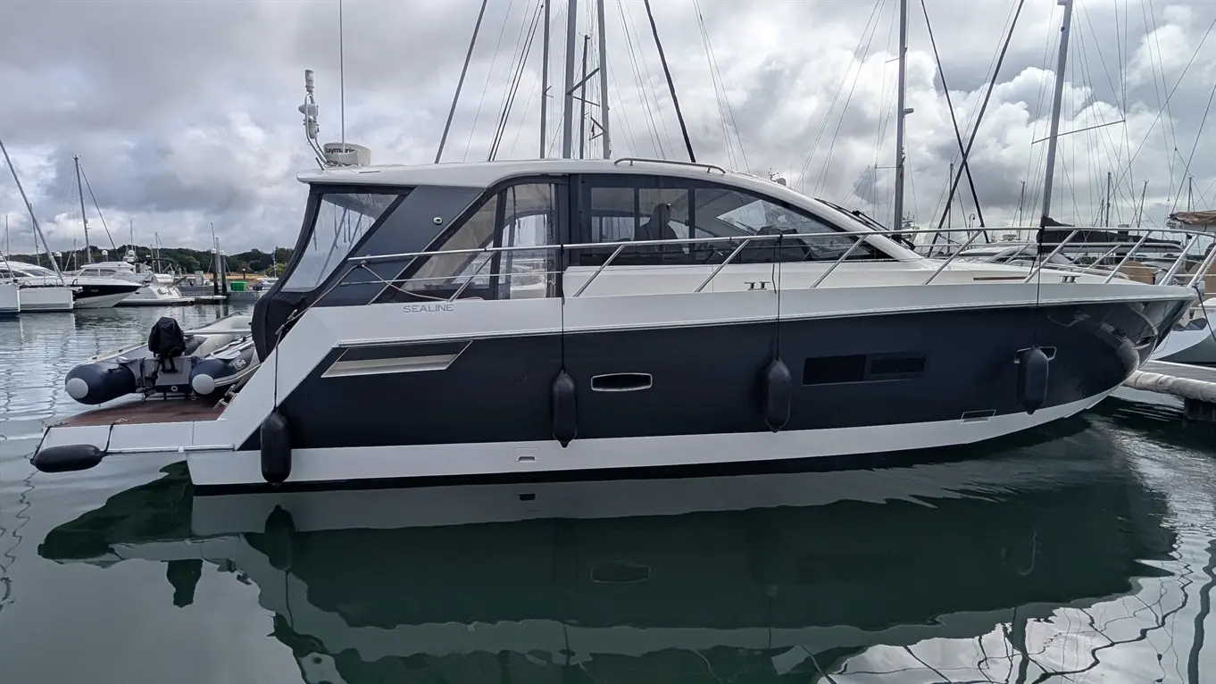 Sealine SC42 motor yacht moored in a marina, shown in profile with white superstructure and dark hull.