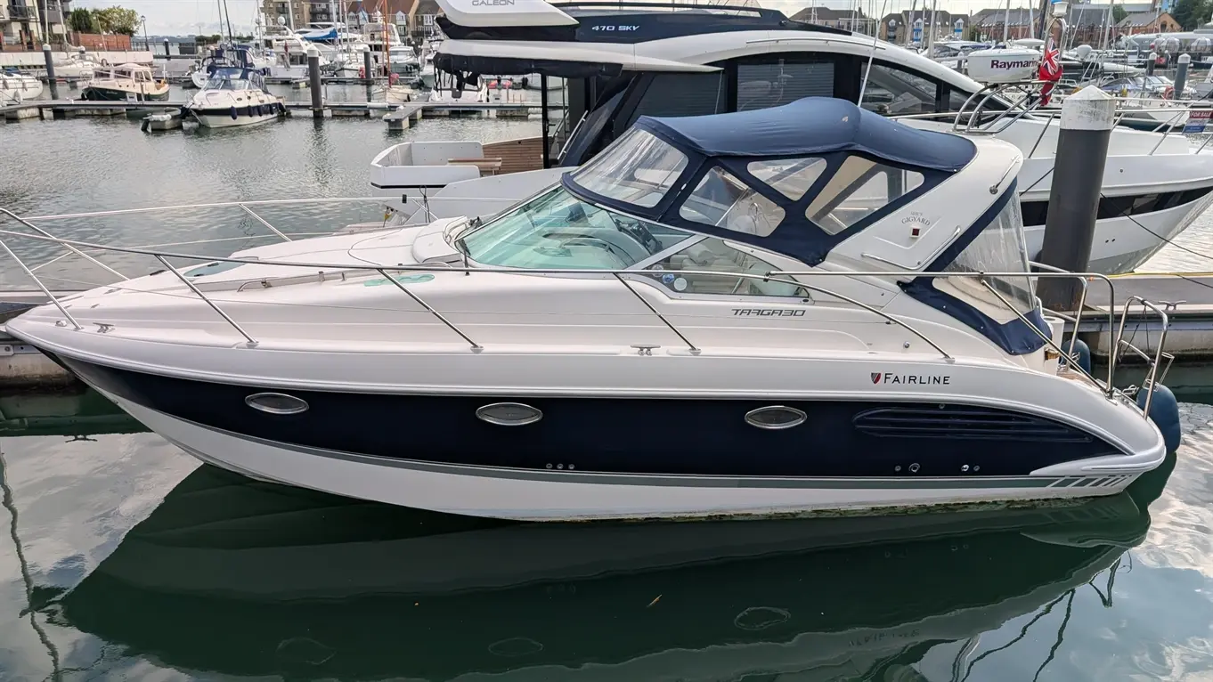 Fairline Targa 30 motor yacht moored in a marina, shown in profile with a navy canopy and white hull.