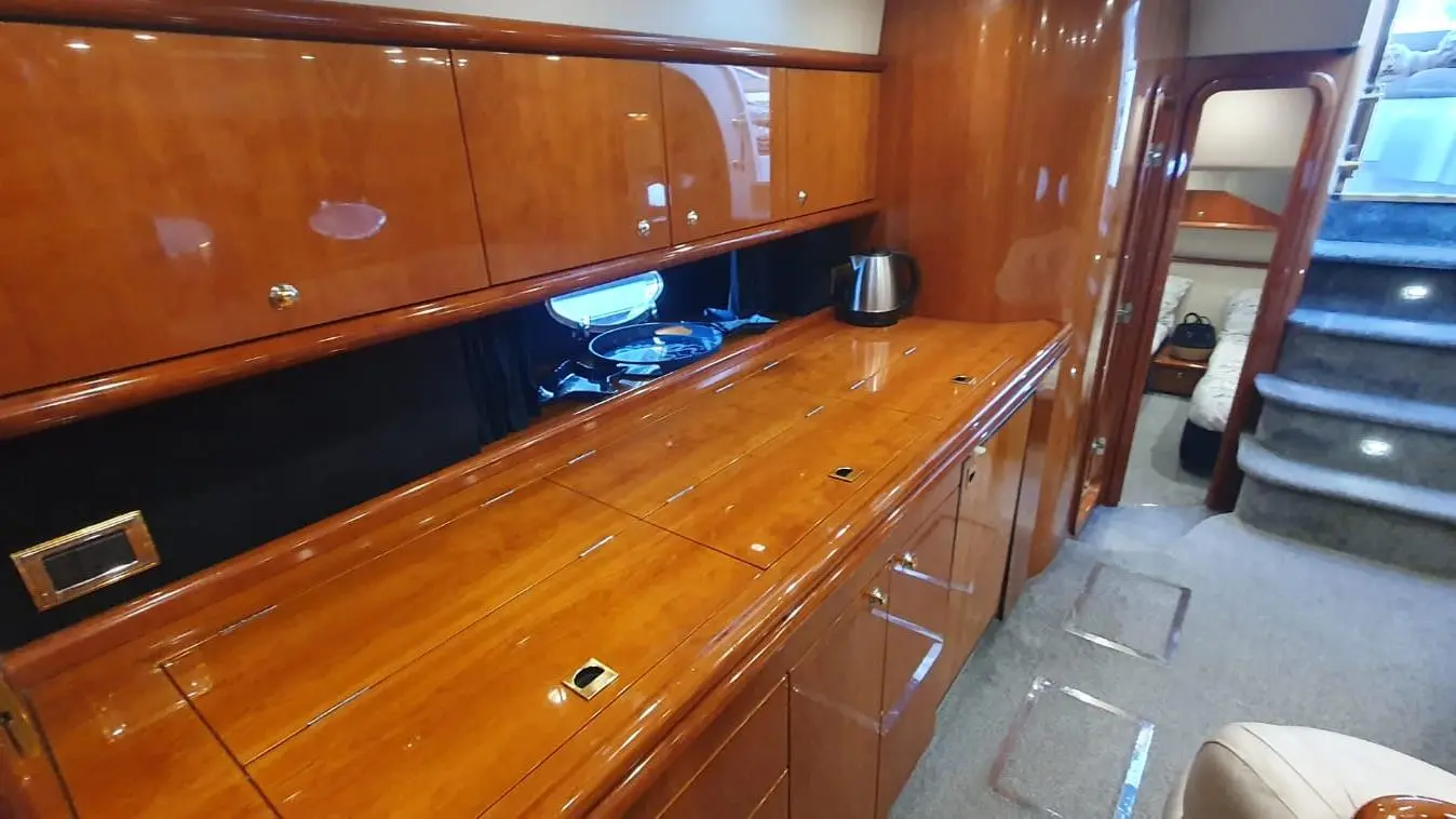 Luxury yacht interior featuring polished wooden cabinetry, a kettle, and a view into the cabin area with steps leading down.