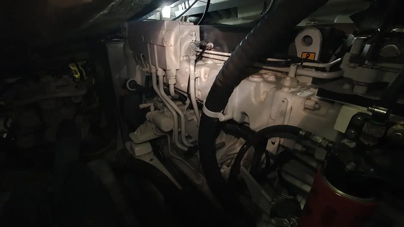 Close-up view of a boat engine compartment, featuring pipes, hoses, and machinery in dim lighting.