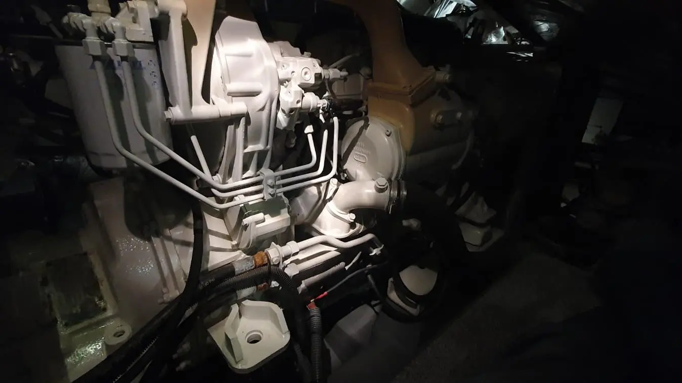Engine compartment showing various pipes, components, and fittings in a dimly lit environment.