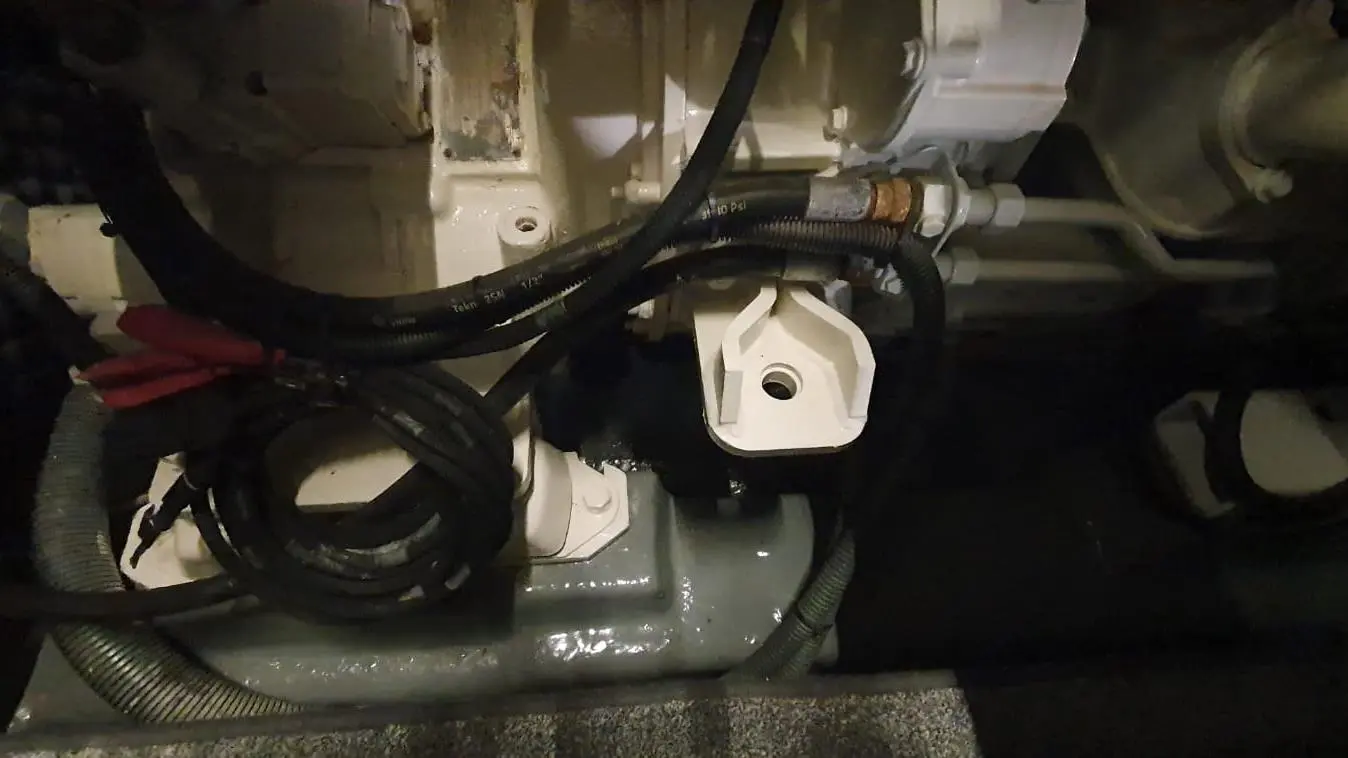 Close-up of engine components with visible hoses and electrical connections in a dark environment, showcasing machinery details.