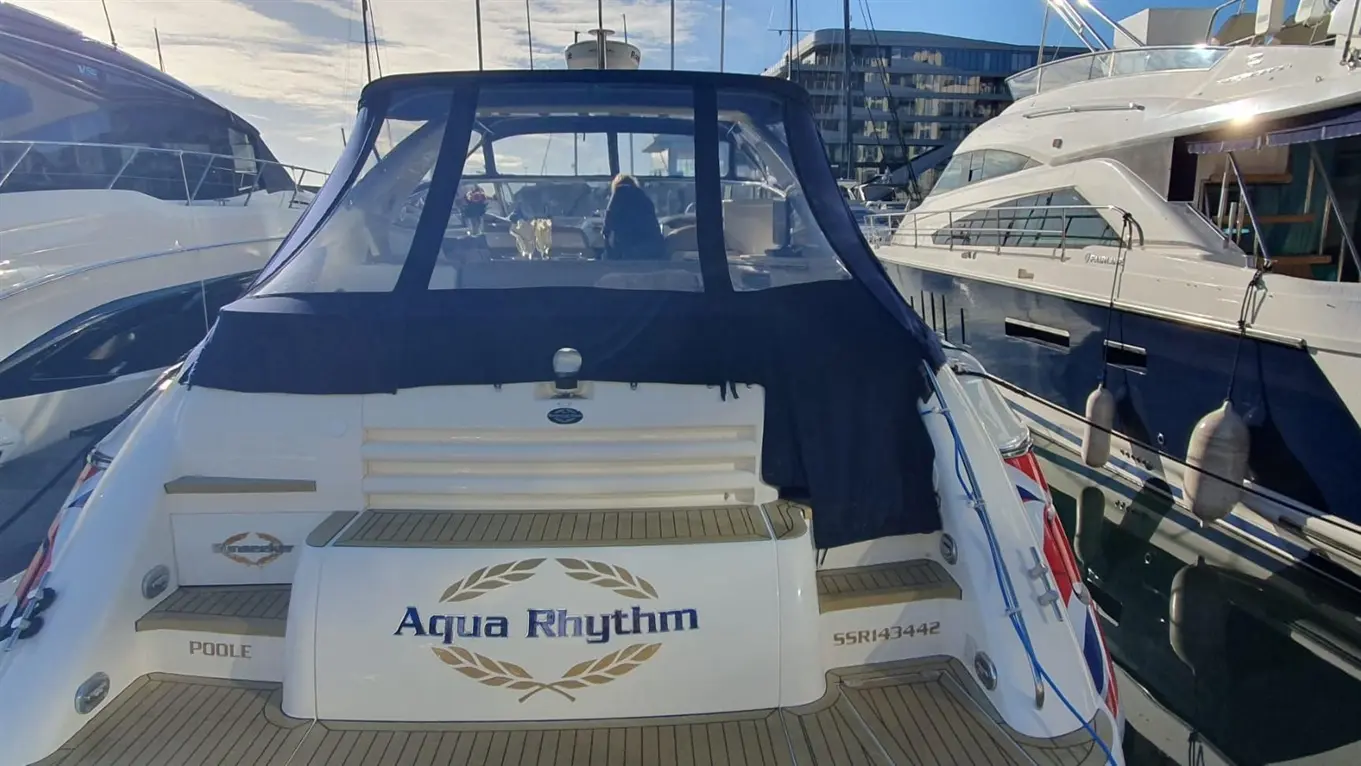 Aqua Rhythm boat moored at a marina, featuring a padded rear deck and visible text "Aqua Rhythm" and "Poole.