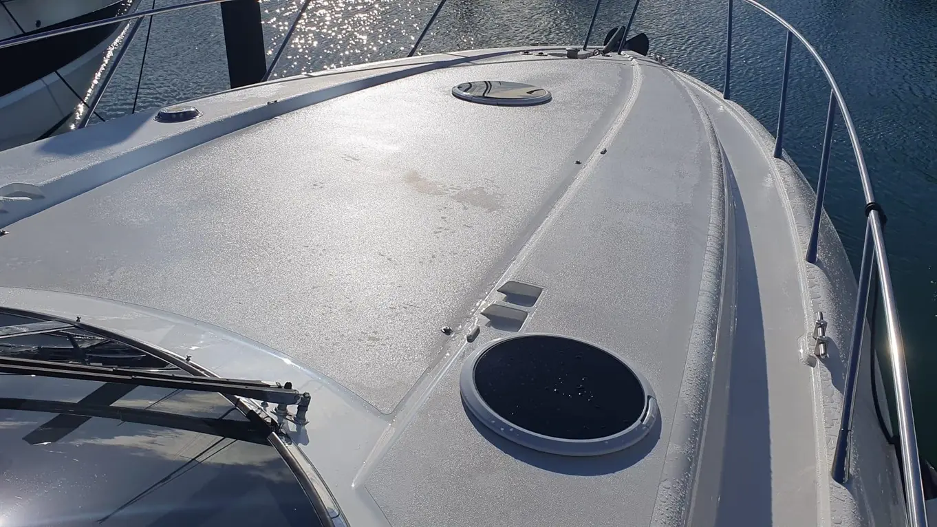 View from the top of a boat showing the deck, circular hatches, and reflections on the water.