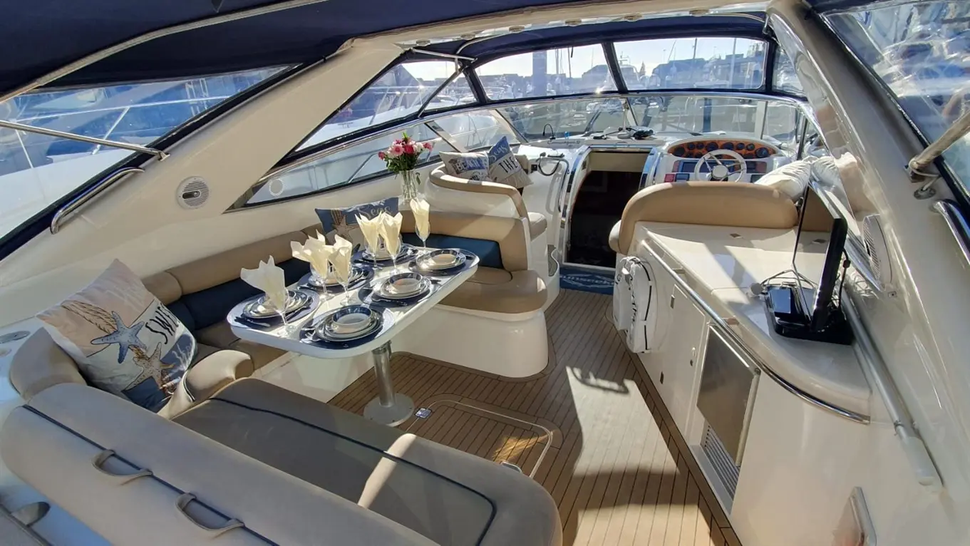 Elegant yacht interior featuring a dining table set with plates and decorative napkins, surrounded by seating and panoramic windows.