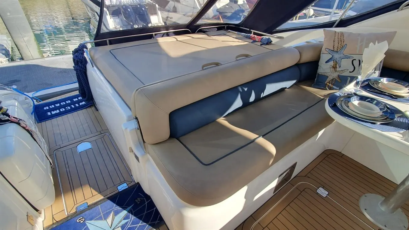 Stylish boat interior with beige seating, a starfish-themed cushion, and a dining table set for a nautical meal.