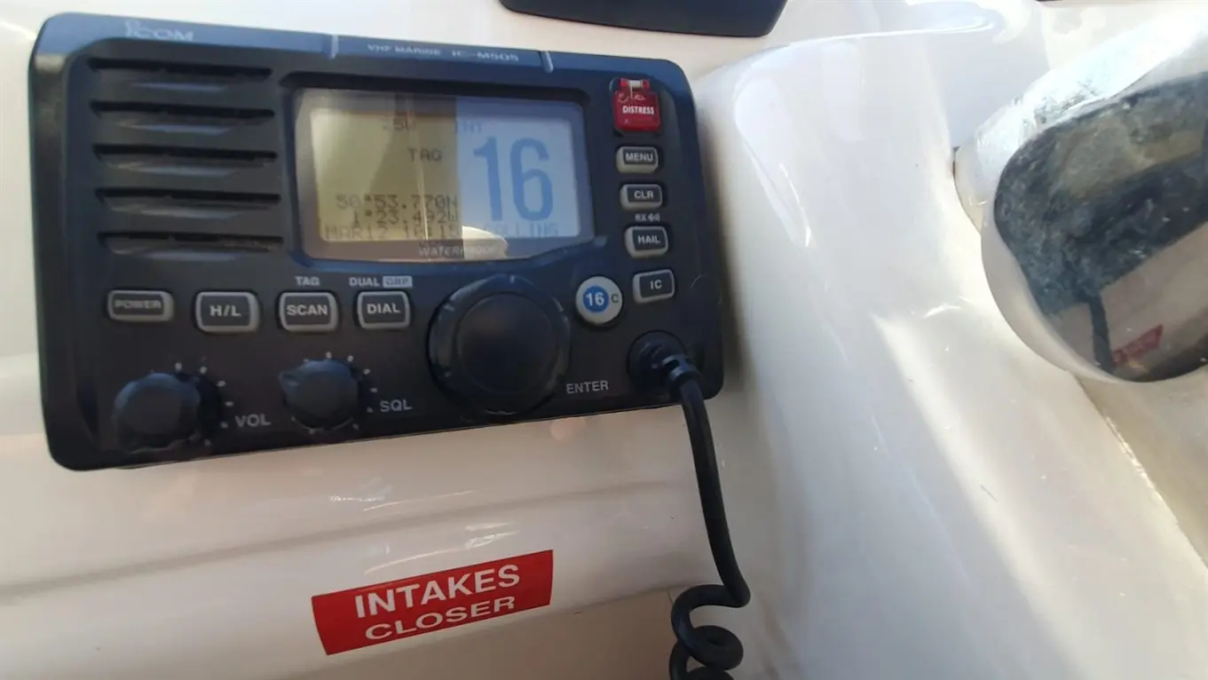 Marine VHF radio display showing channel 16, with a "DISTRESS" button, and a warning label reading "INTAKES CLOSER.