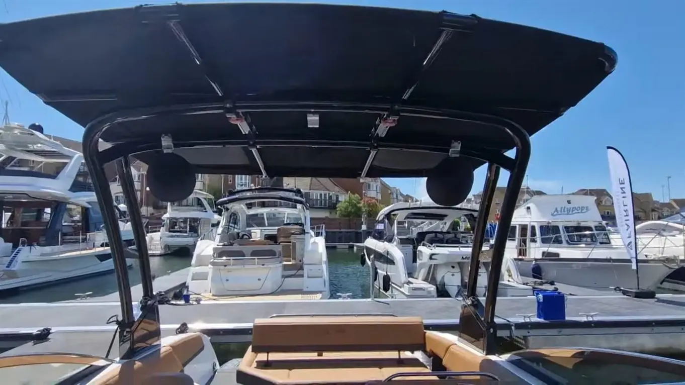 A view from inside a boat, showing the marina, several boats docked, and blue sky above, with a white flag displaying 'VIRGIN'.