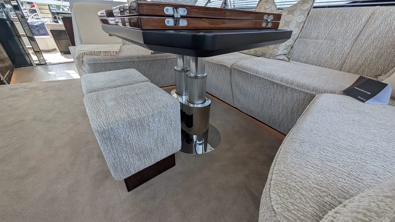 Modern yacht interior featuring a plush seating area, chrome table base, and elegant wooden table with steamer-style chairs.