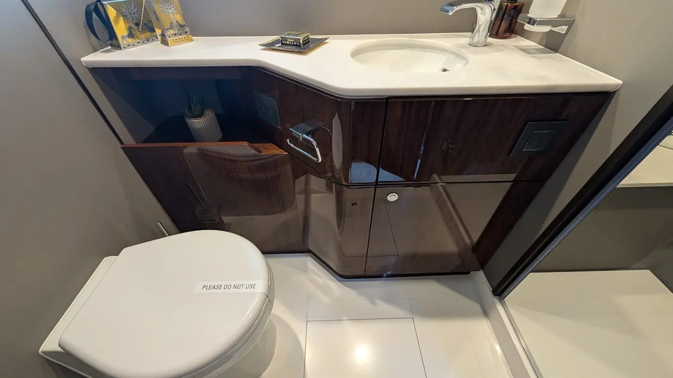Modern bathroom with a white toilet marked "PLEASE DO NOT USE," sleek cabinetry, and a marble sink countertop.
