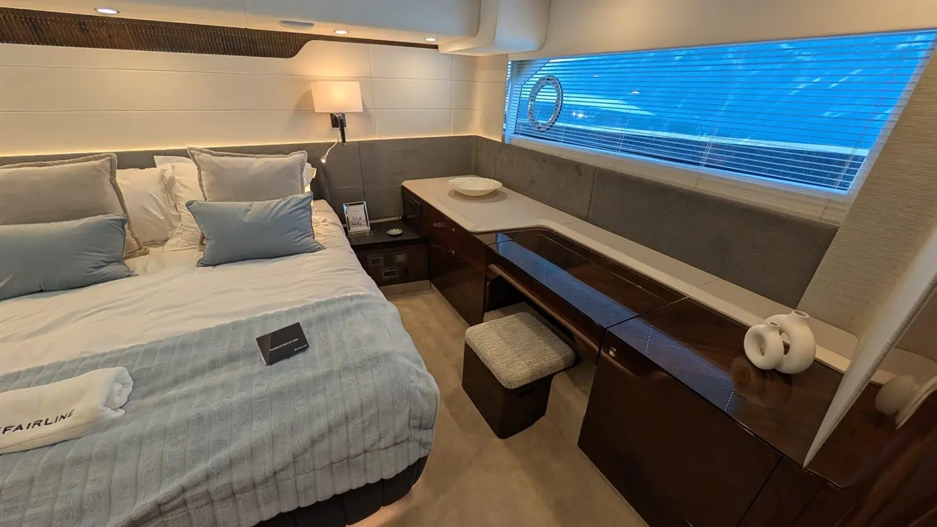 Luxury yacht bedroom featuring a large bed, elegant furnishings, and a view through a window with blinds.