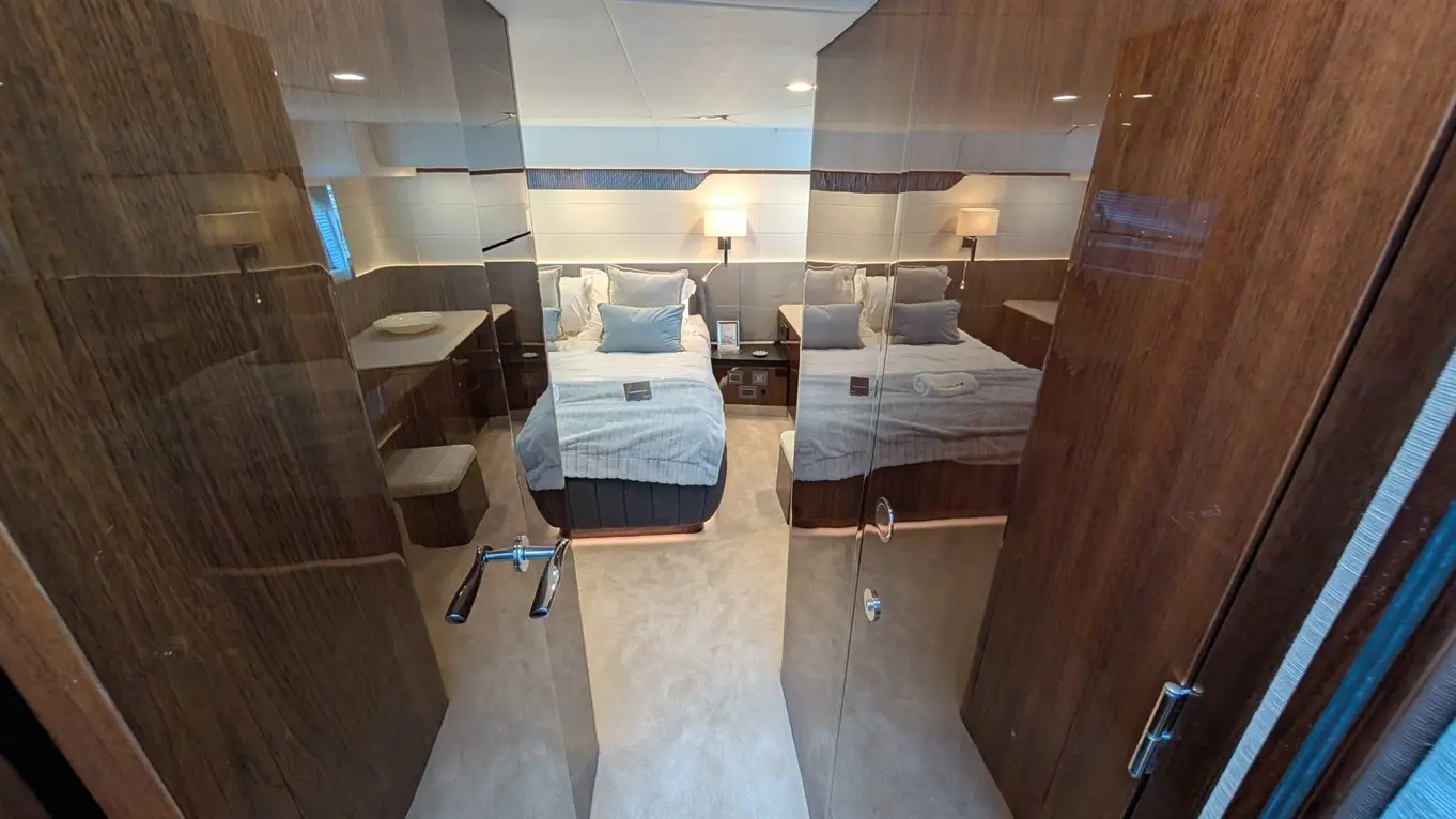 Luxurious cabin with twin beds, soft lighting, wooden finishes, and a spacious feel, viewed through double-glass doors.