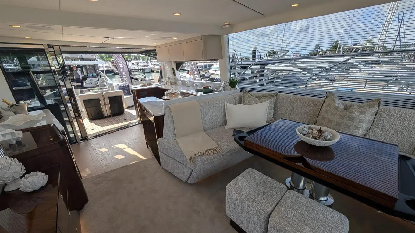 Luxurious yacht interior featuring a spacious seating area with decorative cushions, a view of the marina, and stylish furnishings.
