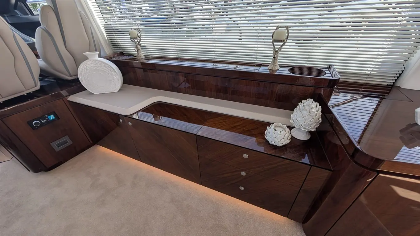 Luxury yacht interior featuring polished wood cabinetry, a white vase, decorative items, and modern controls.