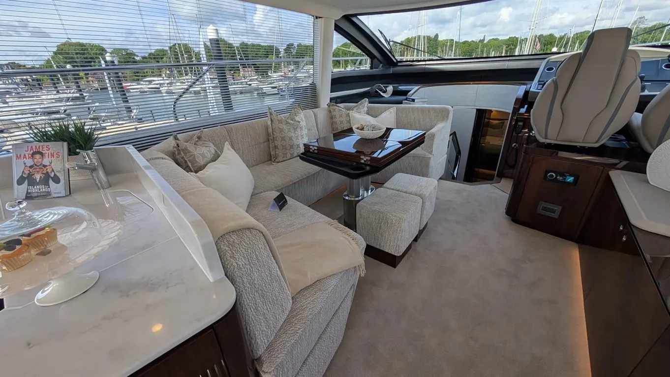 Luxury yacht interior featuring a stylish seating area, coffee table, decorative items, and a view of the marina outside.