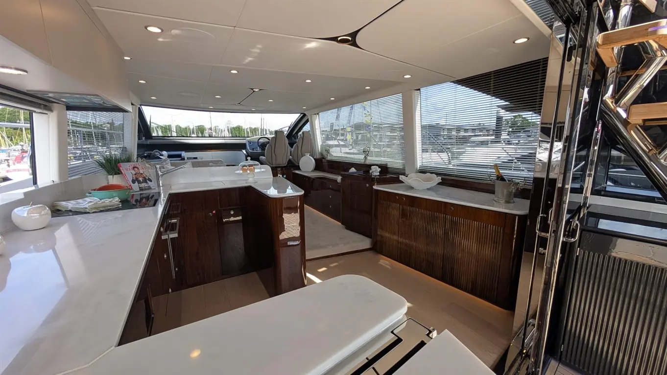 Luxurious yacht interior featuring a modern kitchen, polished surfaces, and a view of the marina through large windows.