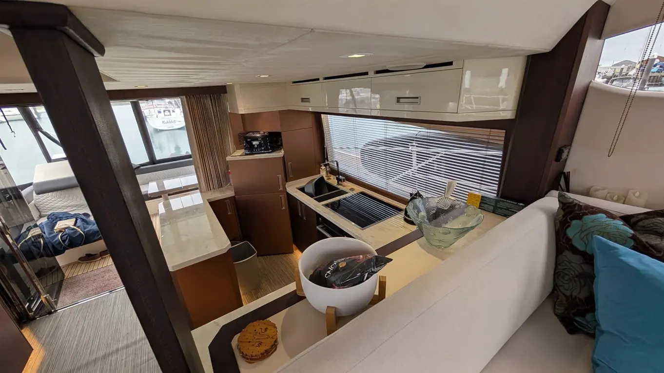 Luxury yacht interior with a modern kitchen, dining area, and views of the marina through large windows.