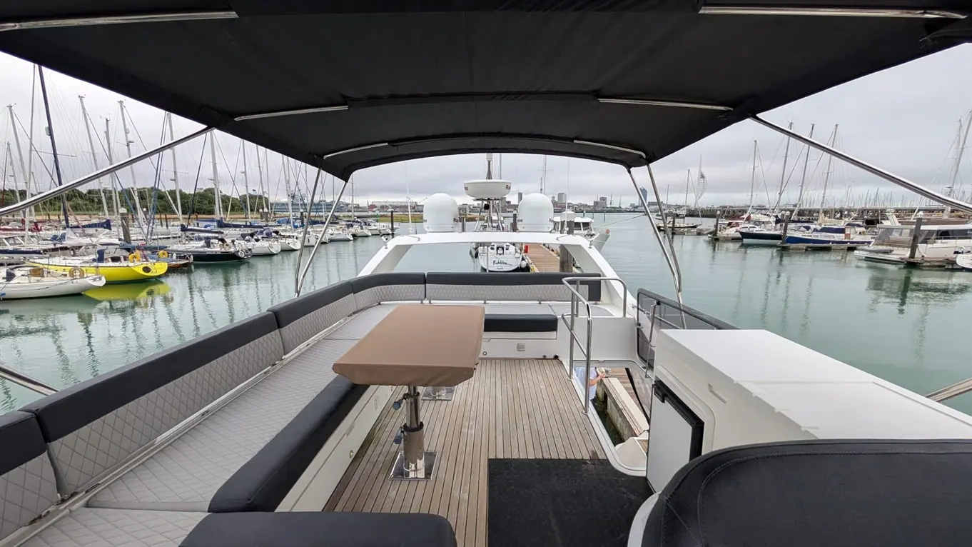 View from a boat's deck overlooking a marina, featuring multiple yachts and a grey sky, with a mounted table and seating area.