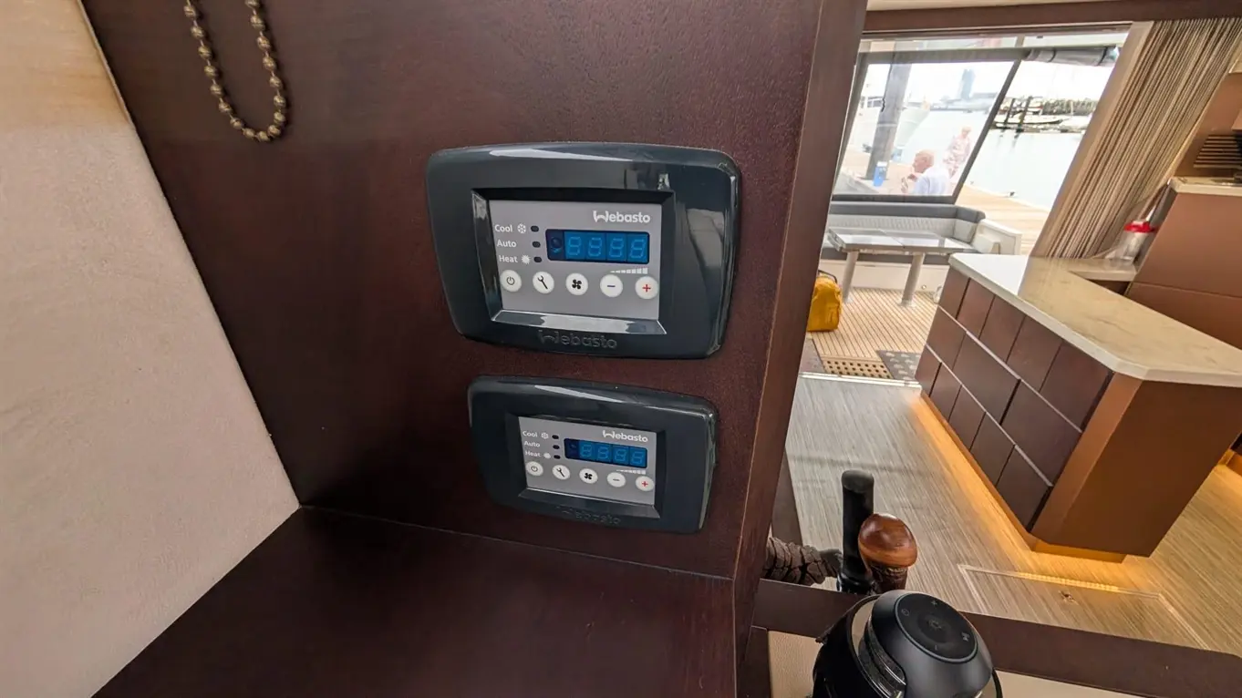 Two Webasto climate control panels mounted on a wooden surface, connected to a stylish boat interior with a view of the marina.