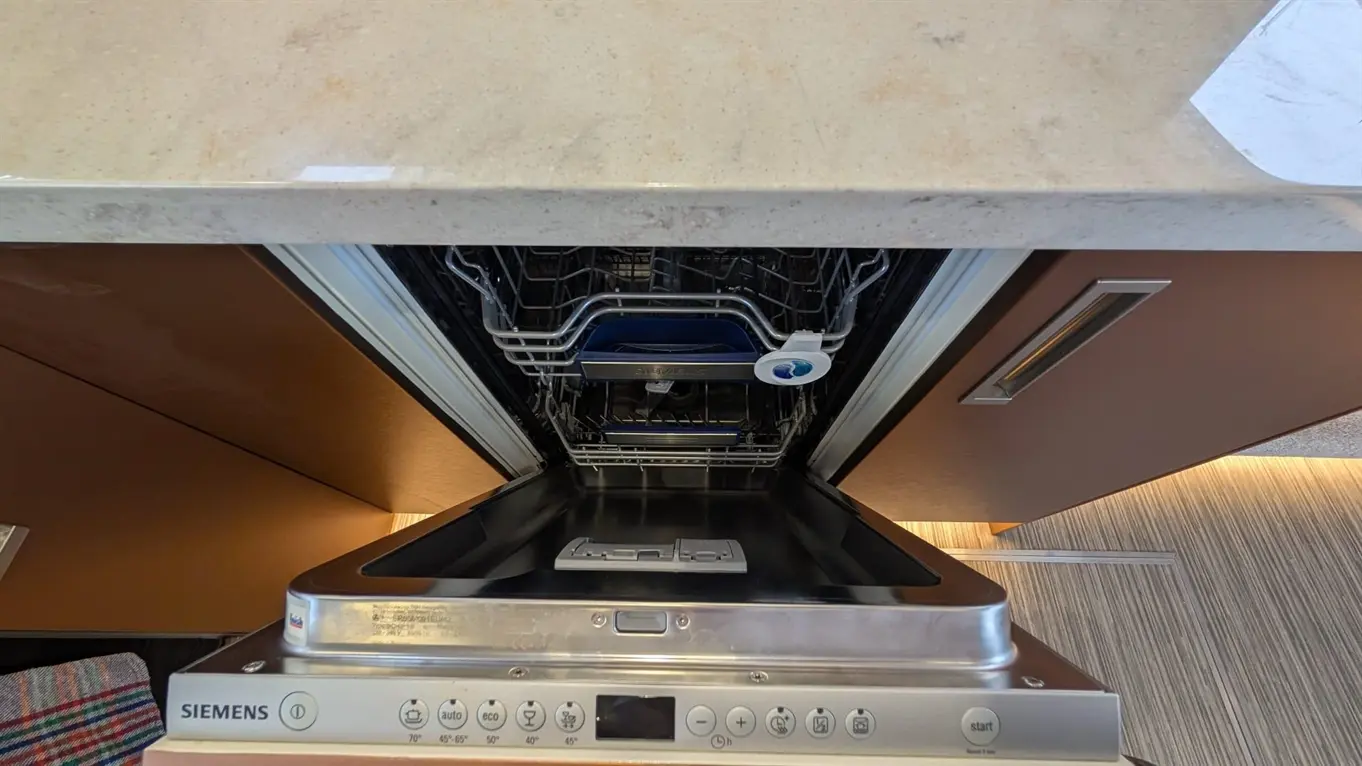 Interior of a Siemens dishwasher showing the empty rack and control panel with start and wash cycle buttons.