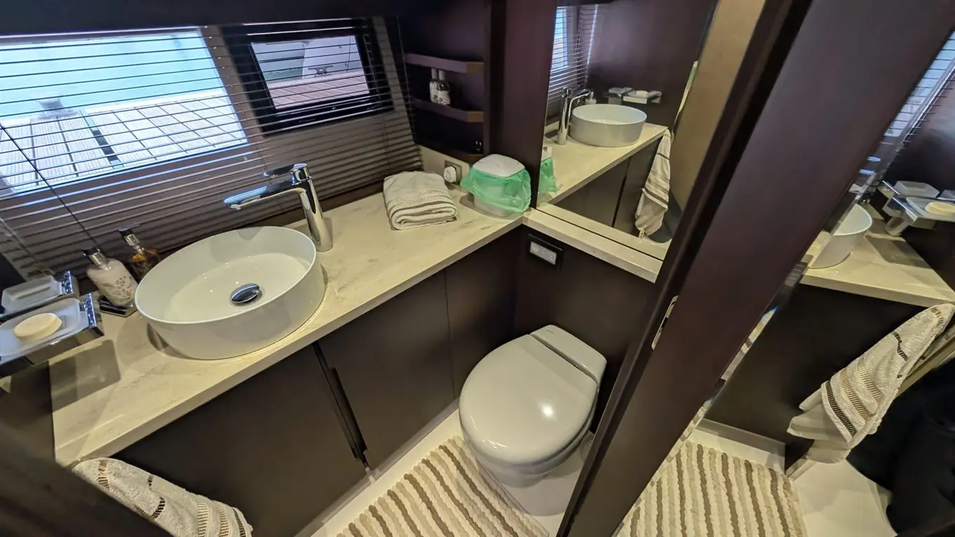 Modern bathroom featuring a round sink, toilet, towels, and a window with blinds, accented by a neutral colour scheme.