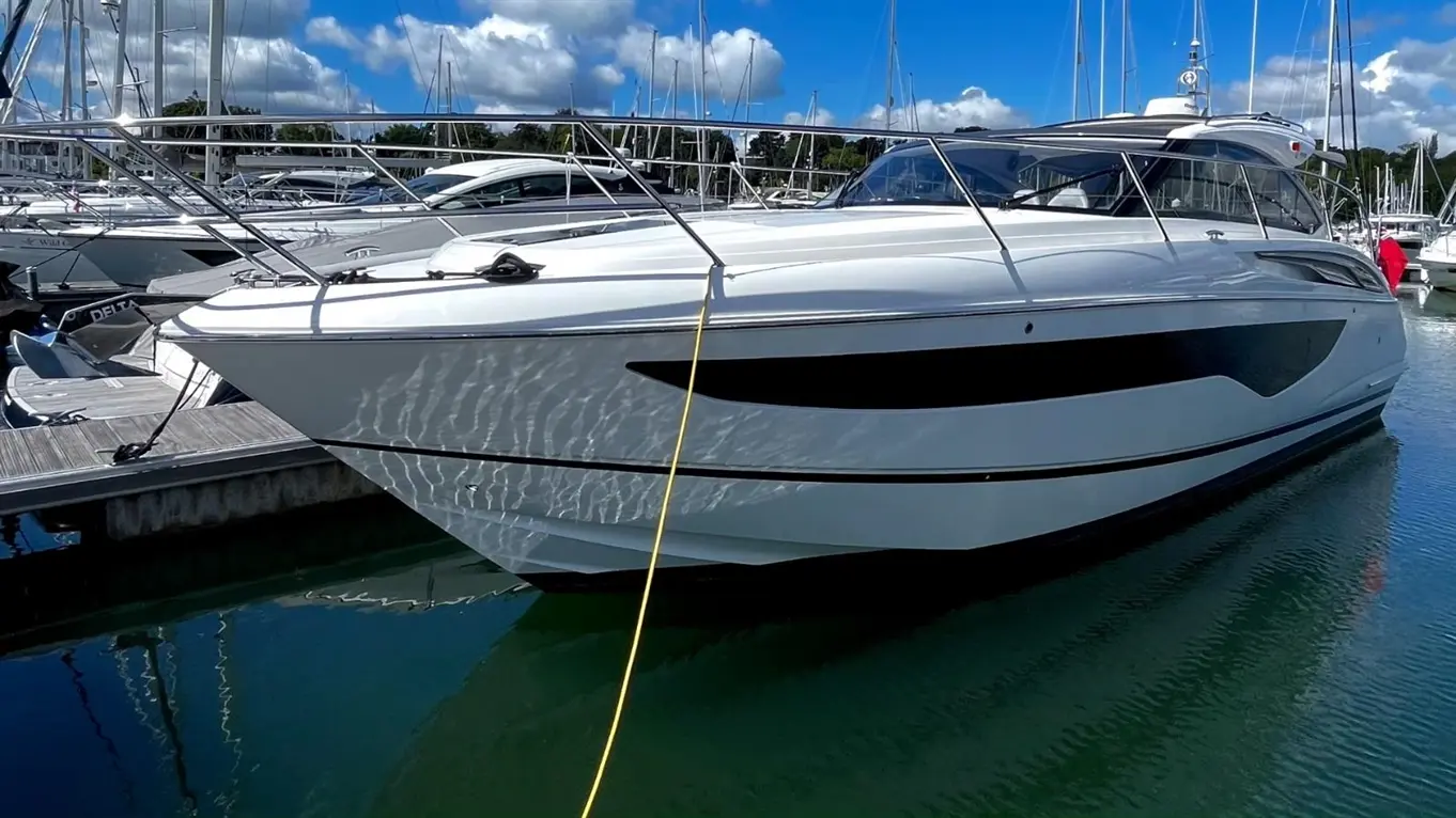Princess V40 motor yacht moored in a marina, viewed from the side under a blue sky.