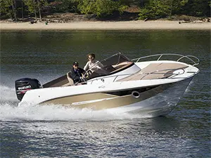 A sleek powerboat speeds across the water with two occupants, showcasing a picturesque shoreline in the background.