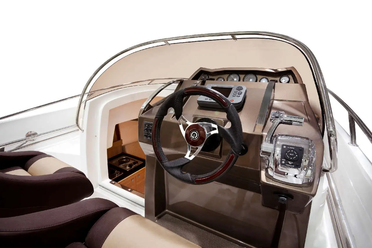 Interior view of a boat's dashboard featuring a steering wheel, control panel, and plush seating.