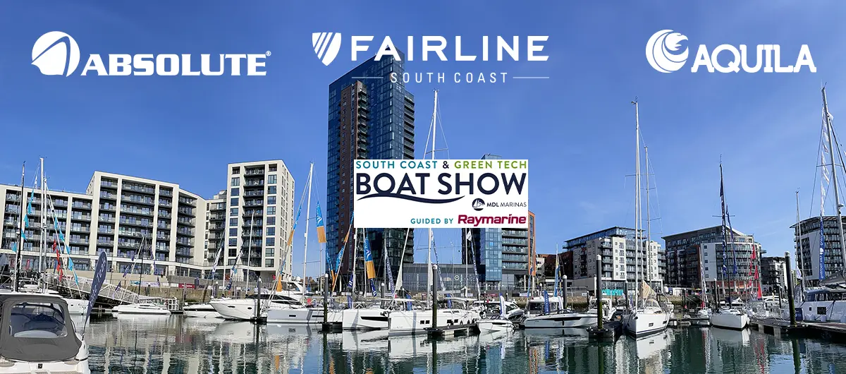 Boats docked at a marina with buildings in the background and signage for the South Coast & Green Tech Boat Show.